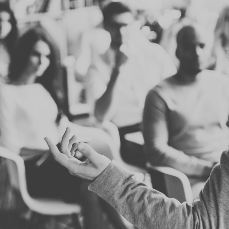 Mann in schwarzem Anzug mit gestreiftem Muster, neutraler Gesichtsausdruck.