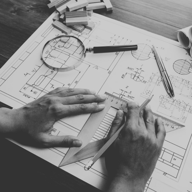 Hände zeichnen auf technischen Plänen mit Lineal und Zirkel.
